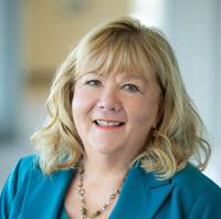 Sharon Torgerson, smiling, wearing a teal suit against a neutral background